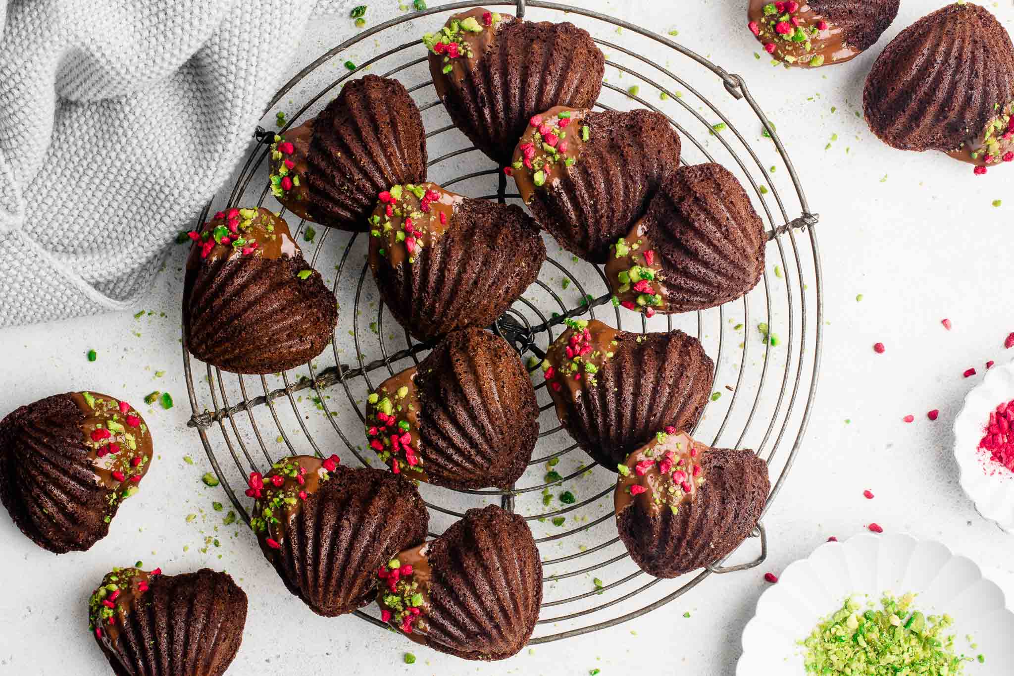 chocolate madeleines dipped in chocolate with pistachios and raspberries