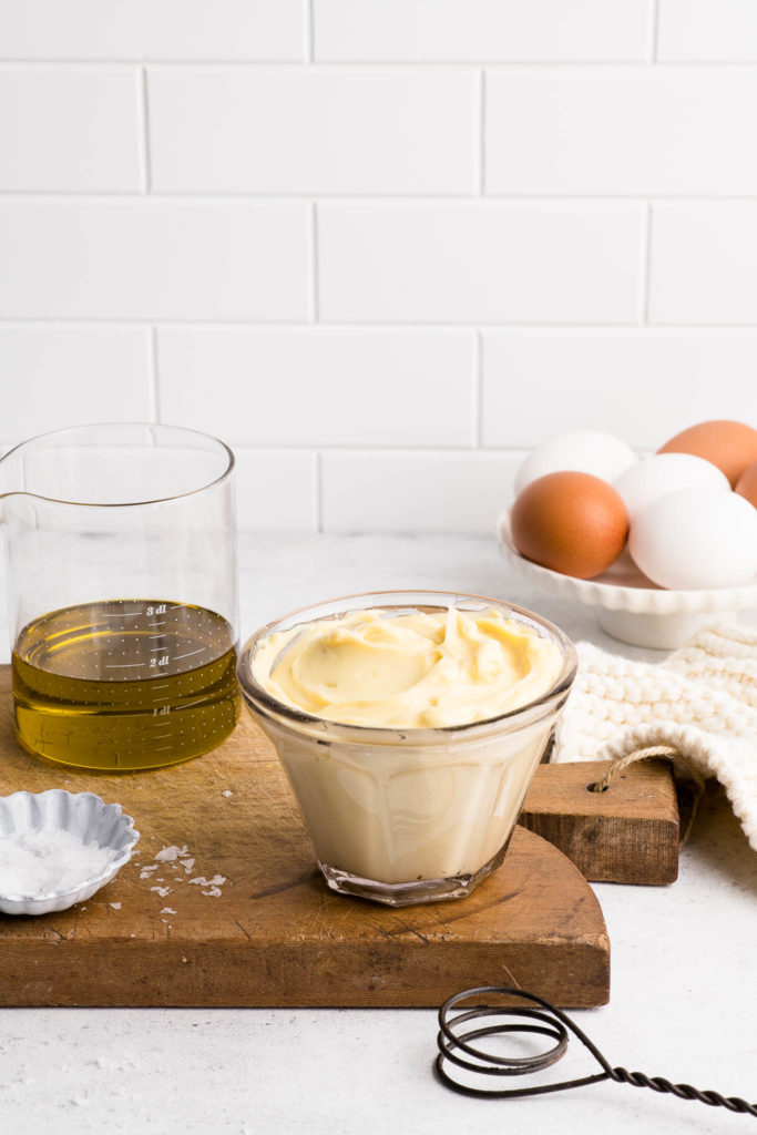 homemade mayonnaise in glass bowl on wooden board