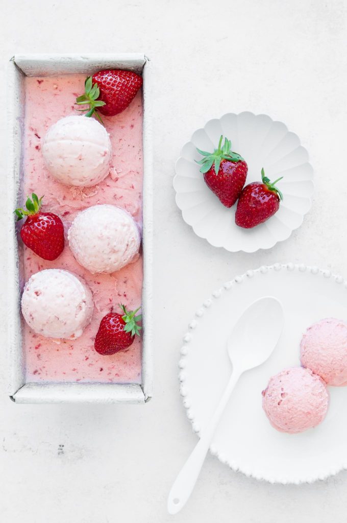 homemade strawberry ice cream in rectangular dish with white plates