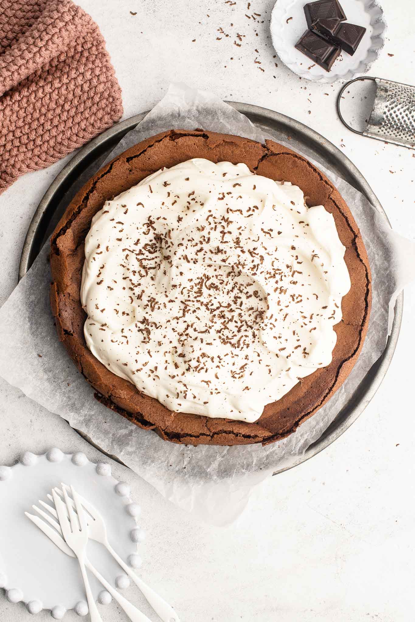 flourless chocolate cake with whipped cream and shaved chocolate on metal tray