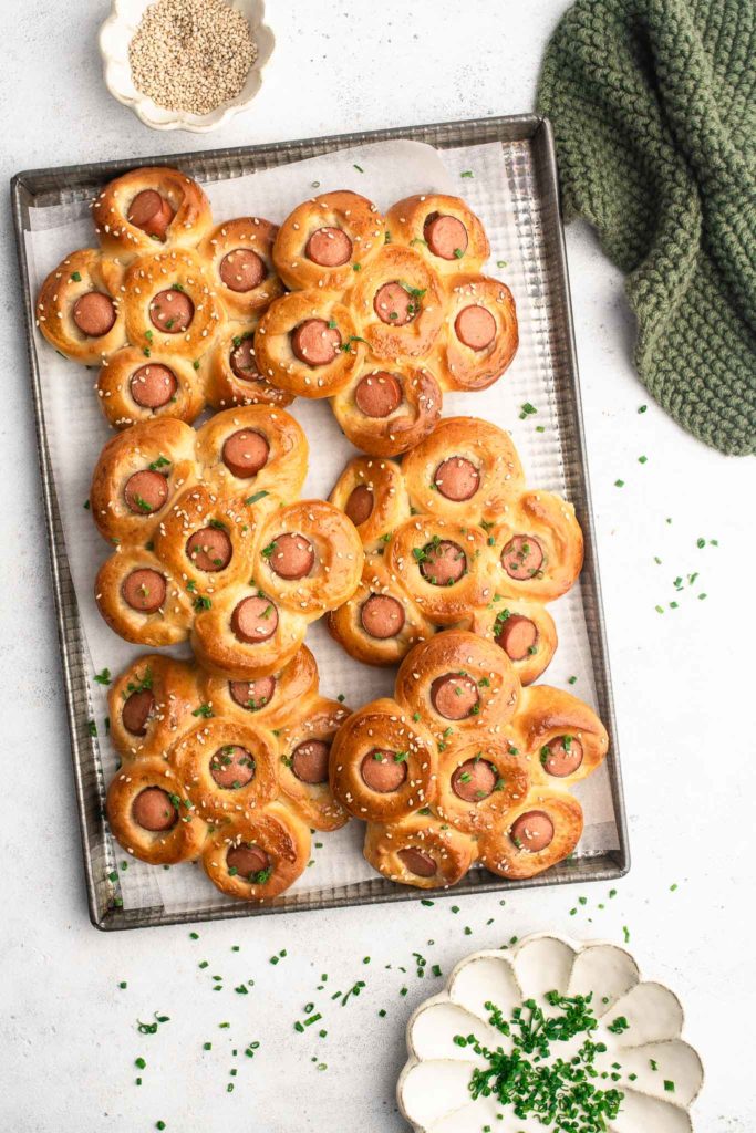 hot dog flower buns on baking tray with sesame seeds and scallions