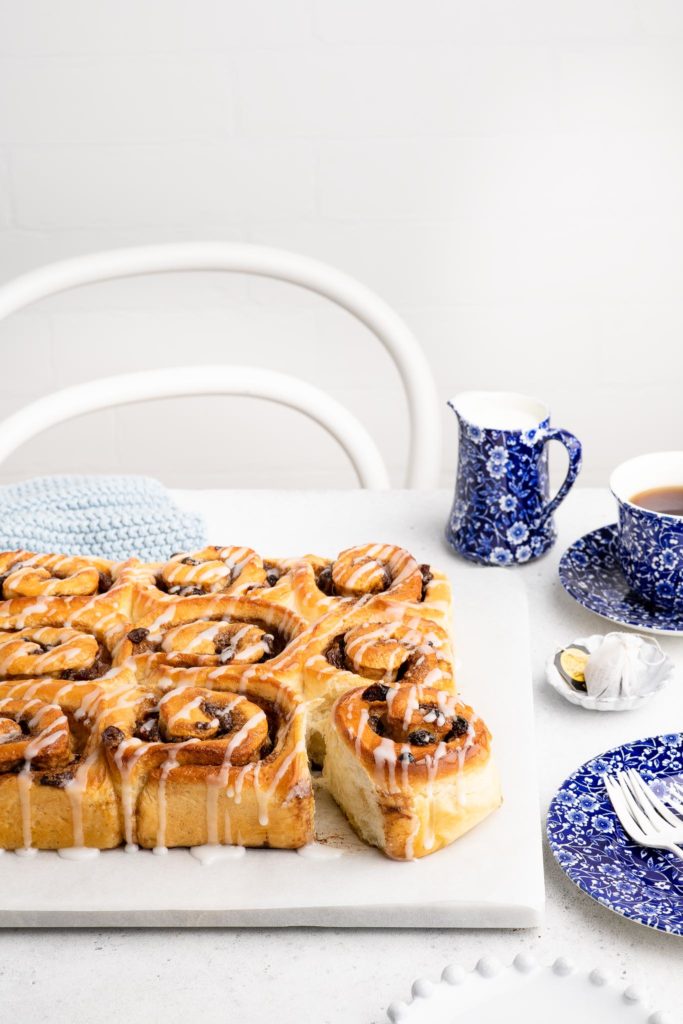 chelsea buns drizzled with icing with cup of tea