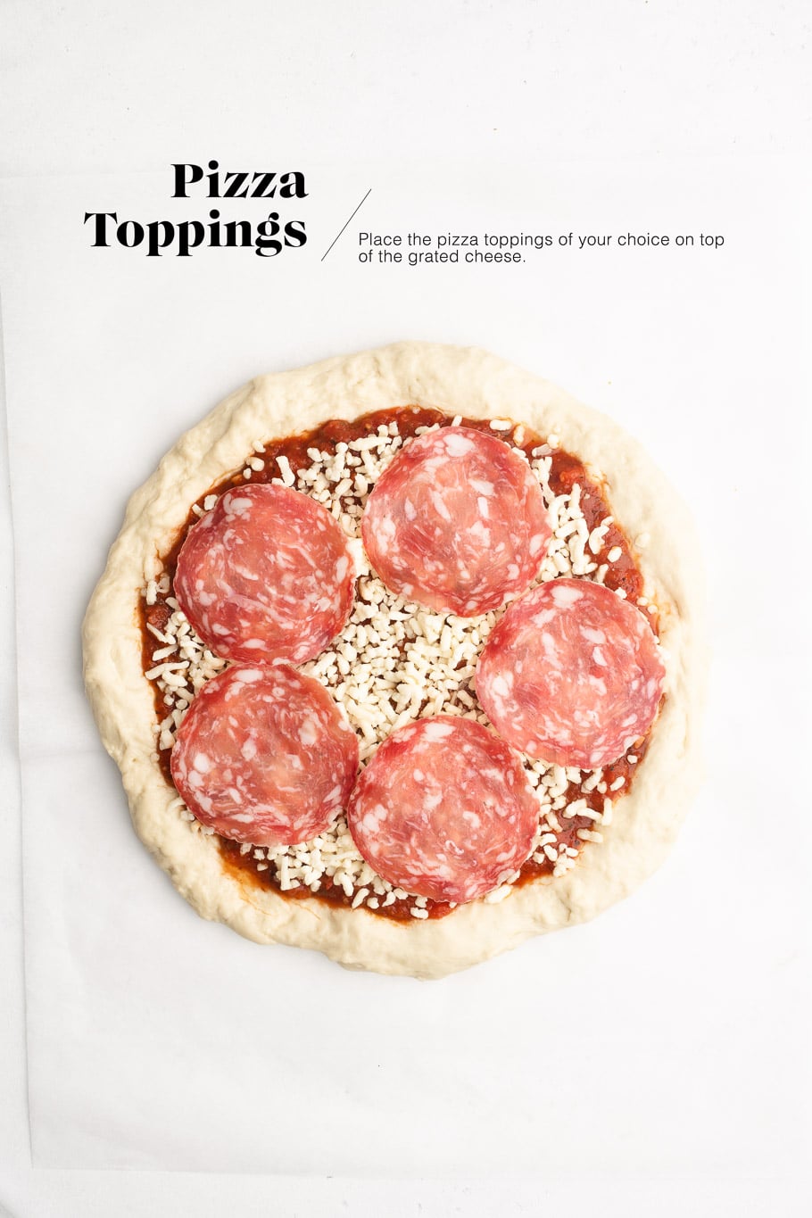 pizza dough with tomato sauce, grated cheese and salami