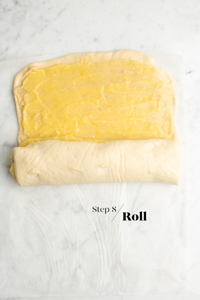 dough spread with lemon curd rolled up on baking paper