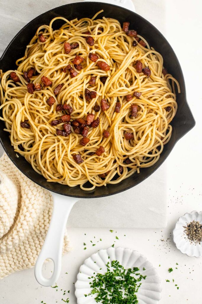 pasta with pancetta in skillet on marble table