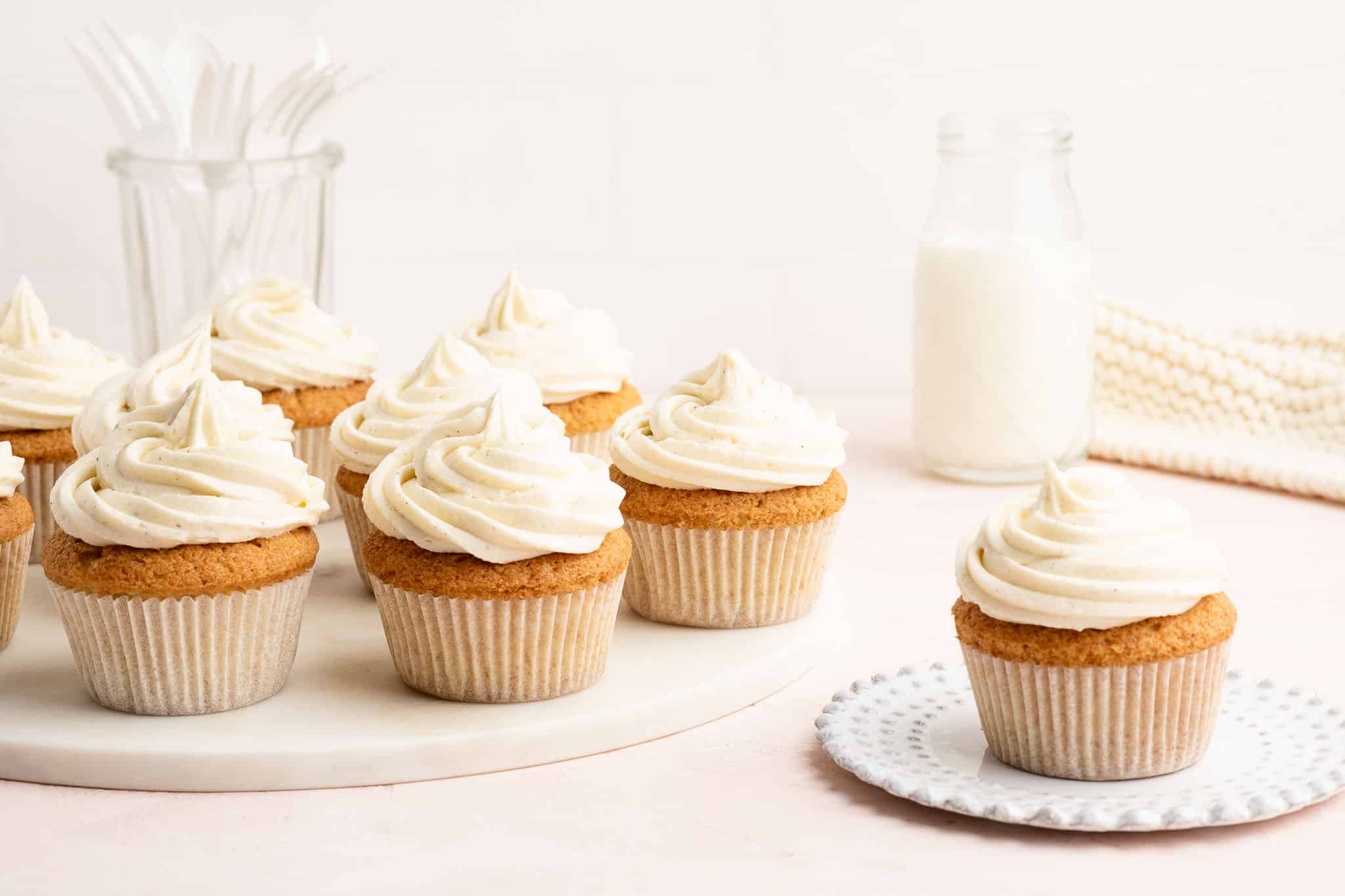 plain vanilla cupcakes with plain vanilla buttercream frosting on pink table