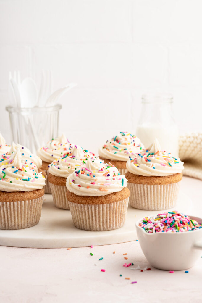 vanilla cupcakes with vanilla buttercream frosting with bowl of sprinkles