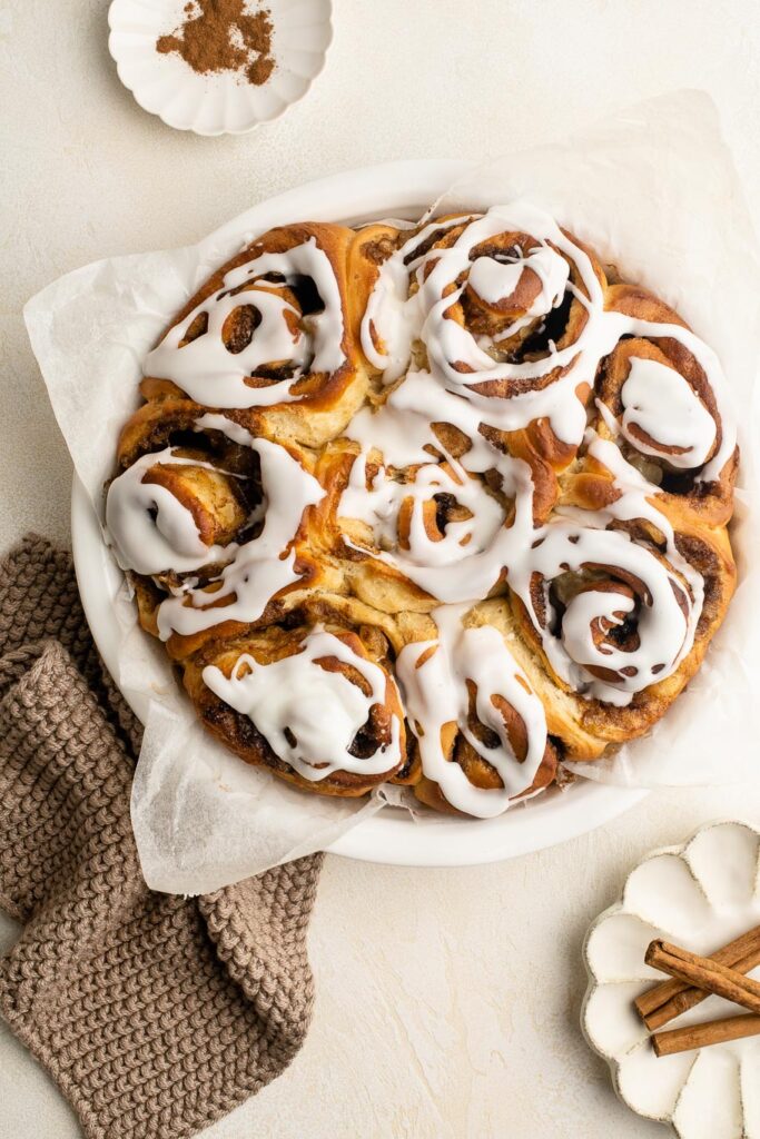 apple cinnamon rolls with frosting in dish with brown cloth