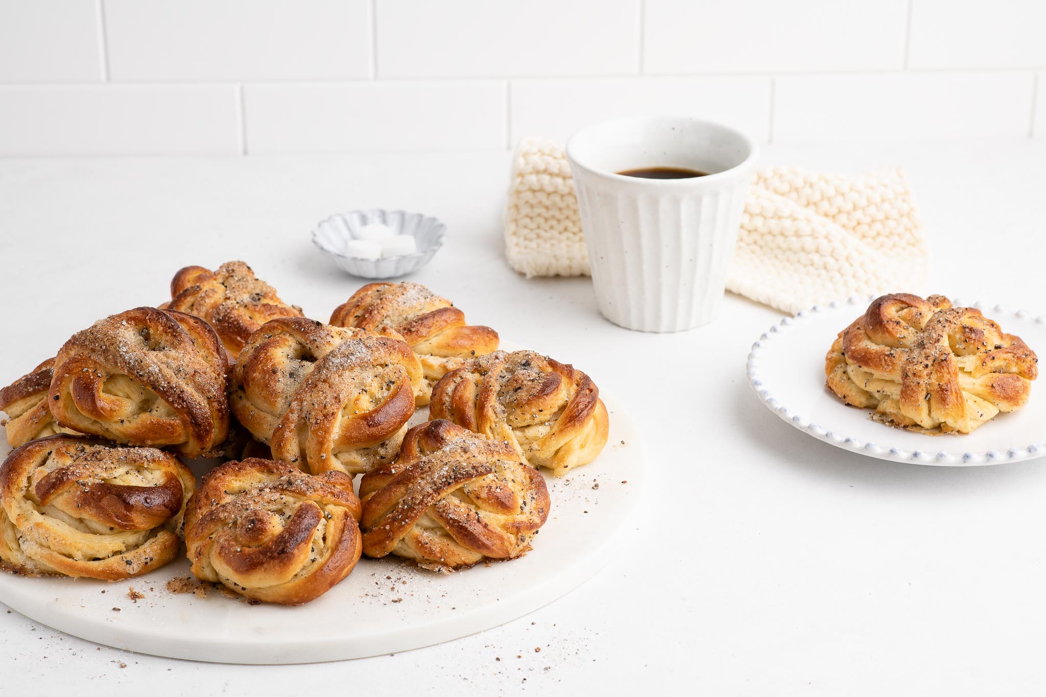 cardamom buns on white plate with coffee