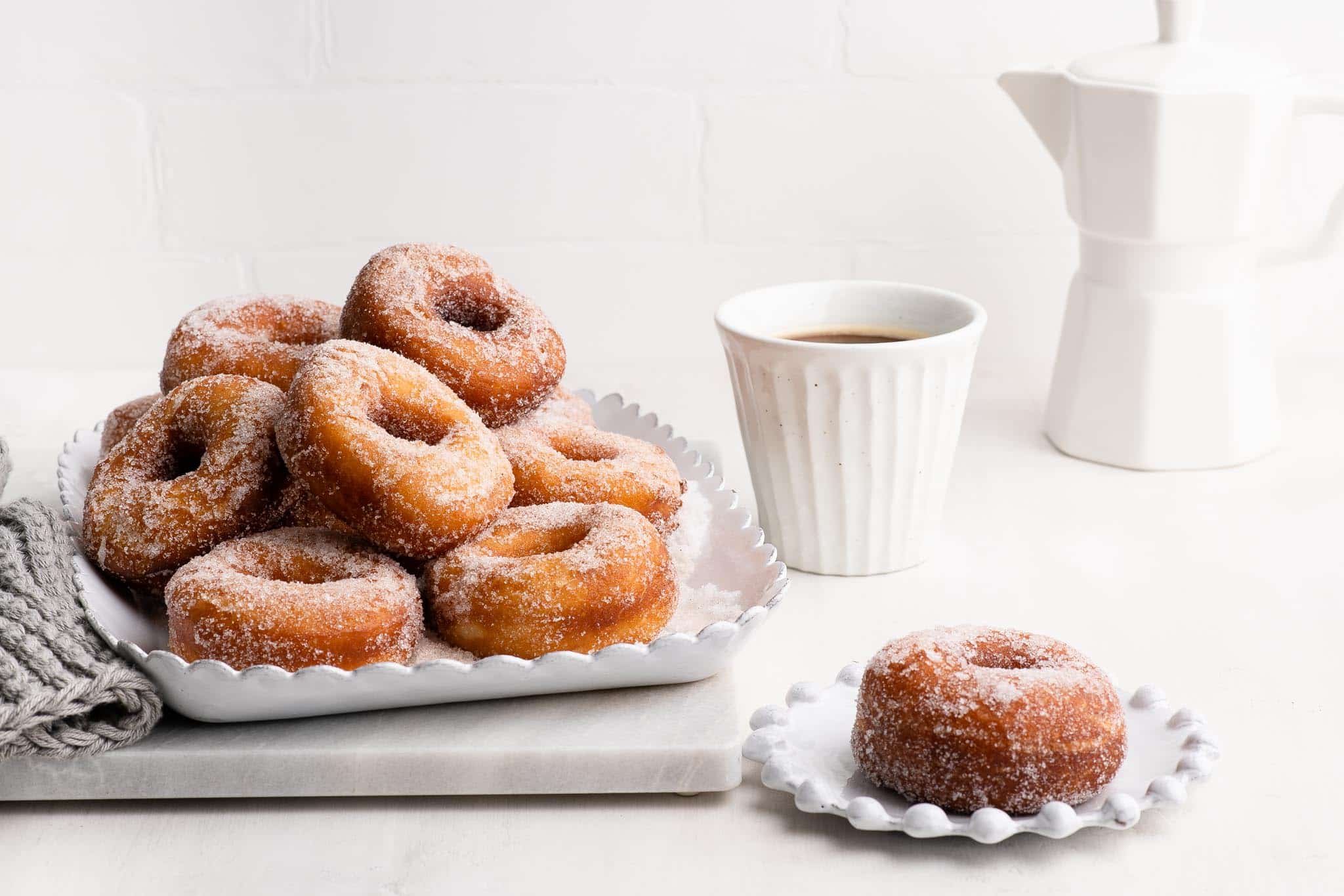 plate of cinnamon sugar donuts with a cup of coffee
