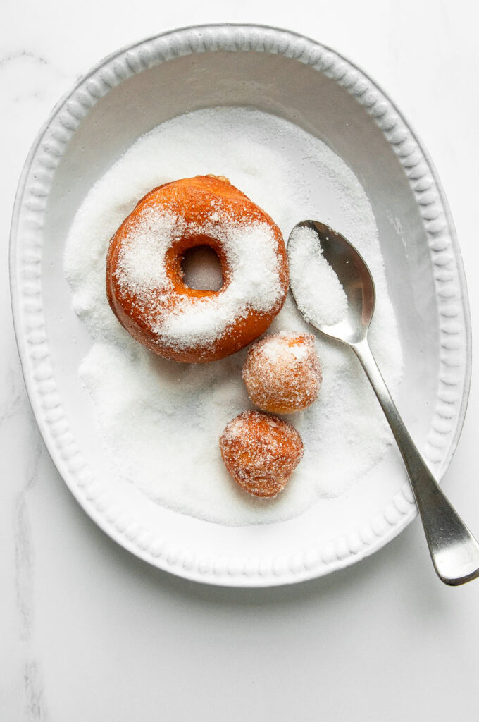 sprinkling sugar on homemade donuts