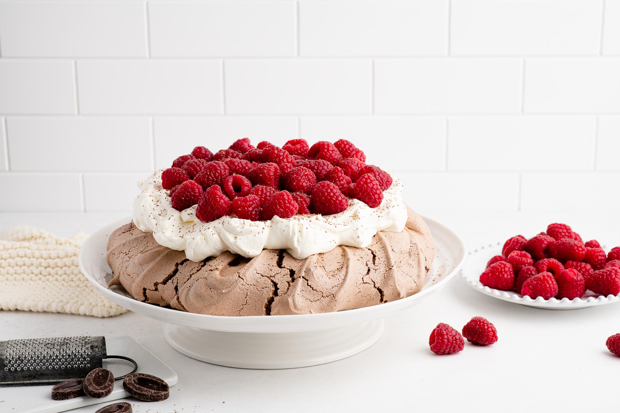 chocolate pavlova with raspberries on white cake stand