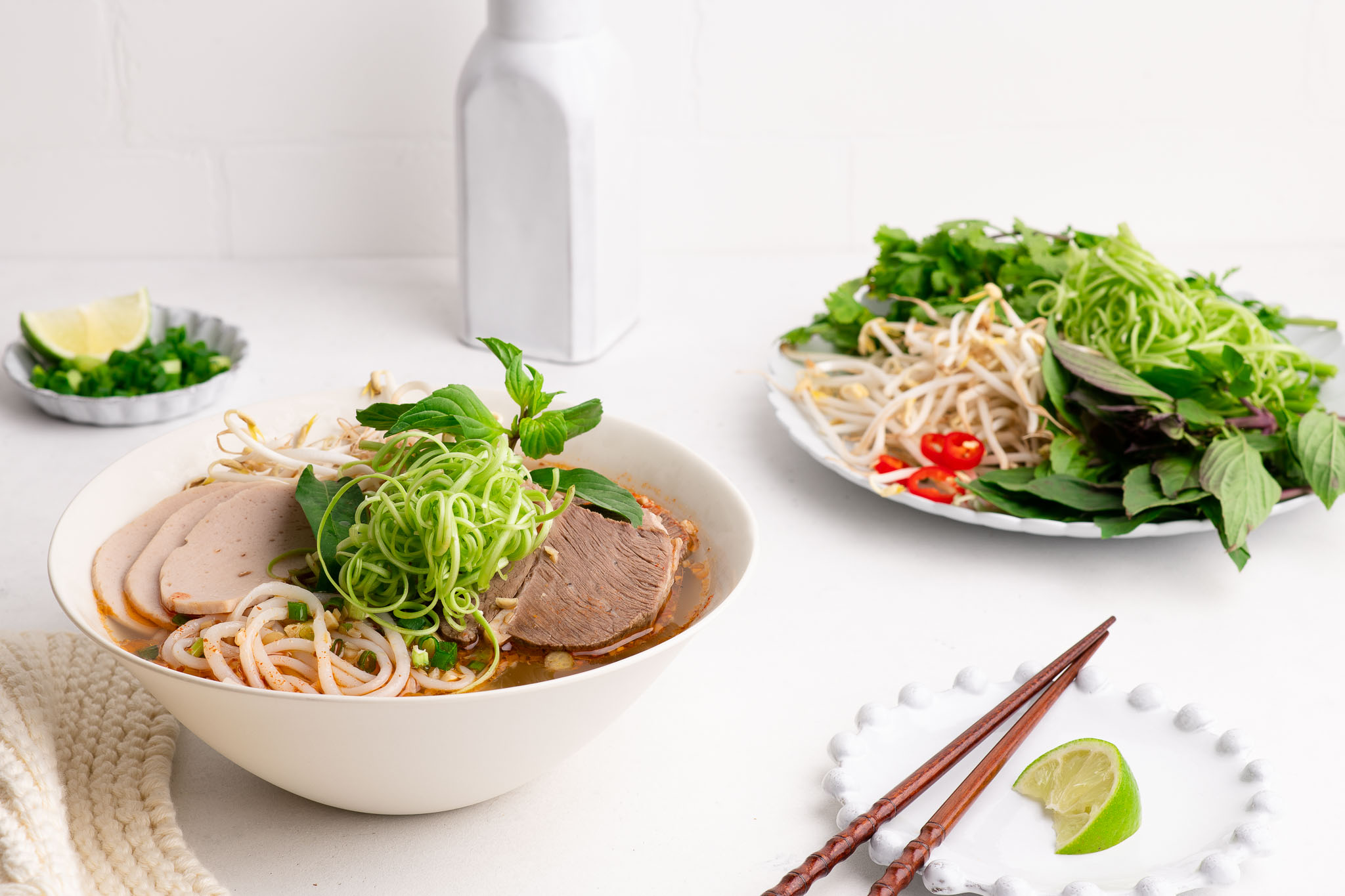 bun bo hue with fresh herbs in noodle bowl