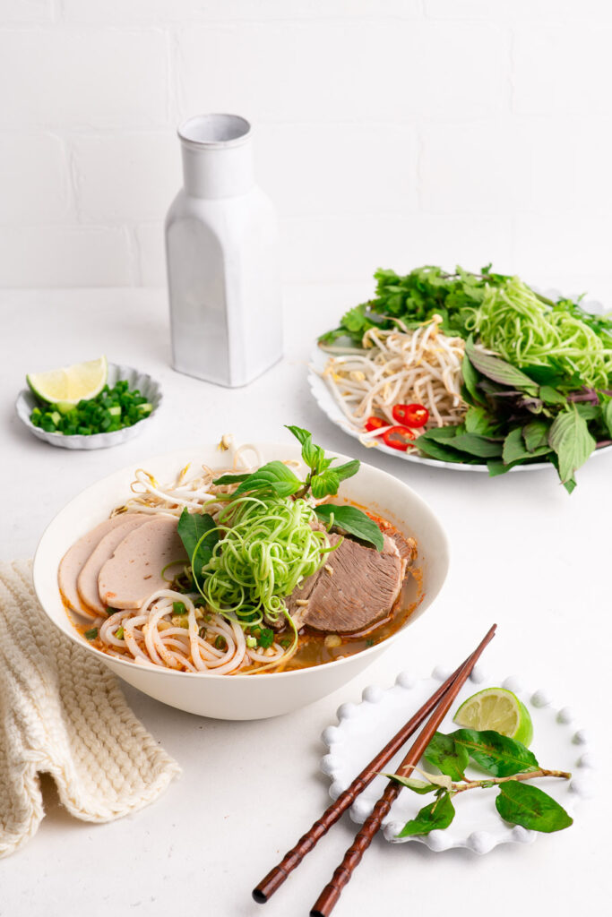 bun bo hue with fresh herbs and water spinach