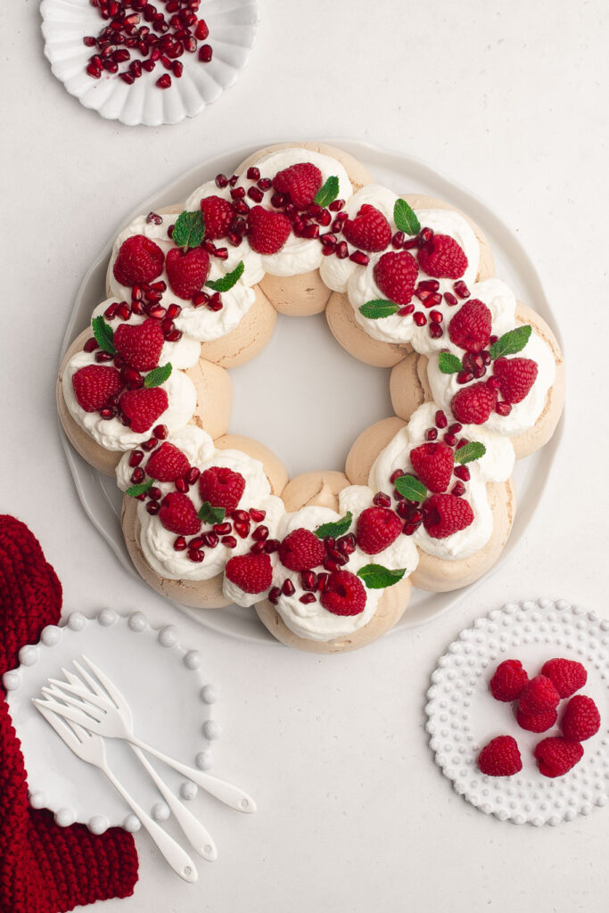 pavlova wreath with red berries on white platter