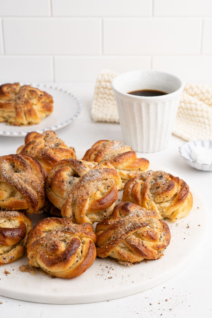 cardamom buns on marble plate with cup of coffee