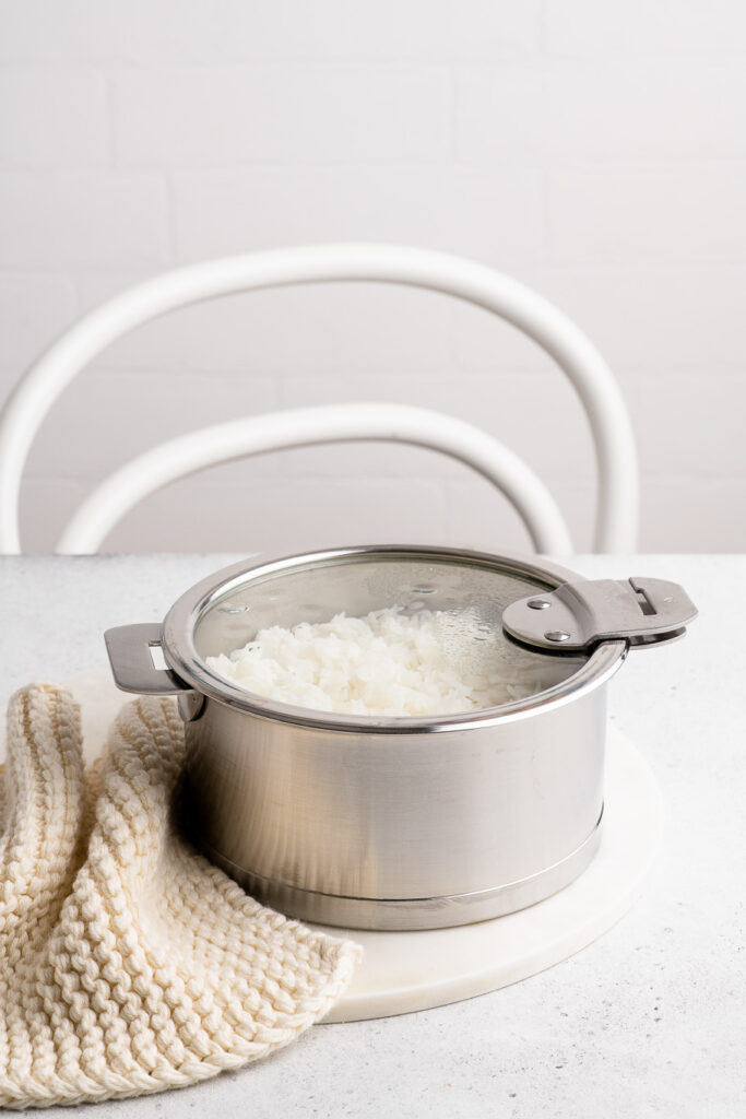 steamed rice in stainless steel pan with glass lid
