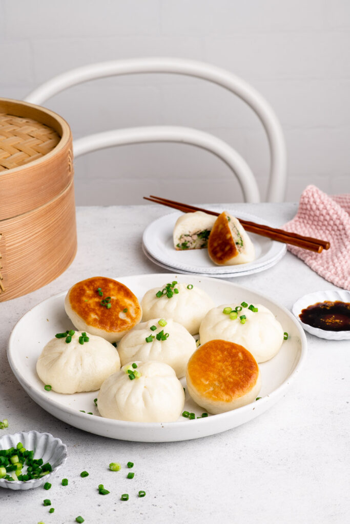 crispy pan-fried pork buns with fresh chives on white plate