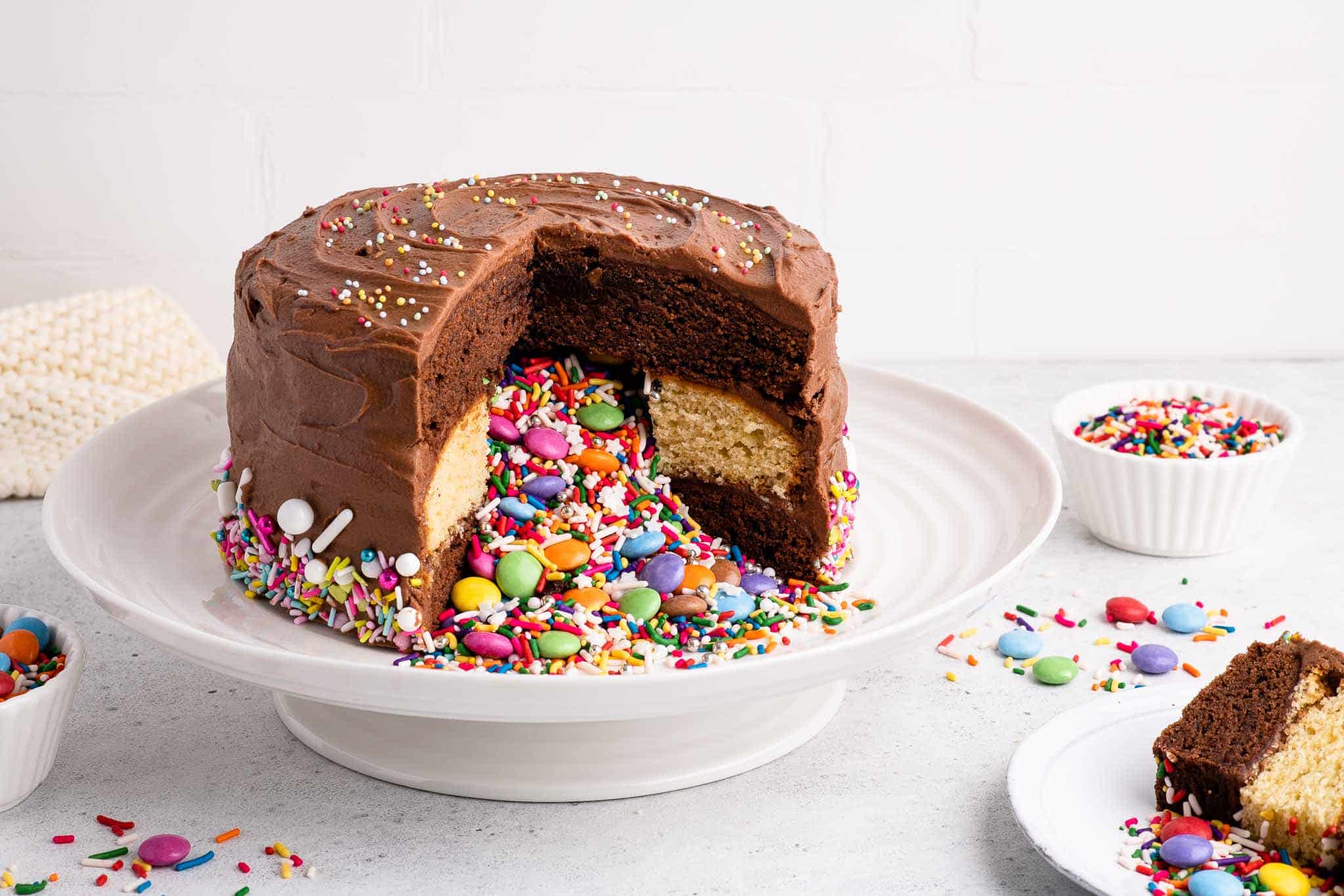 piñata cake filled with smarties and sprinkles on white cake plate