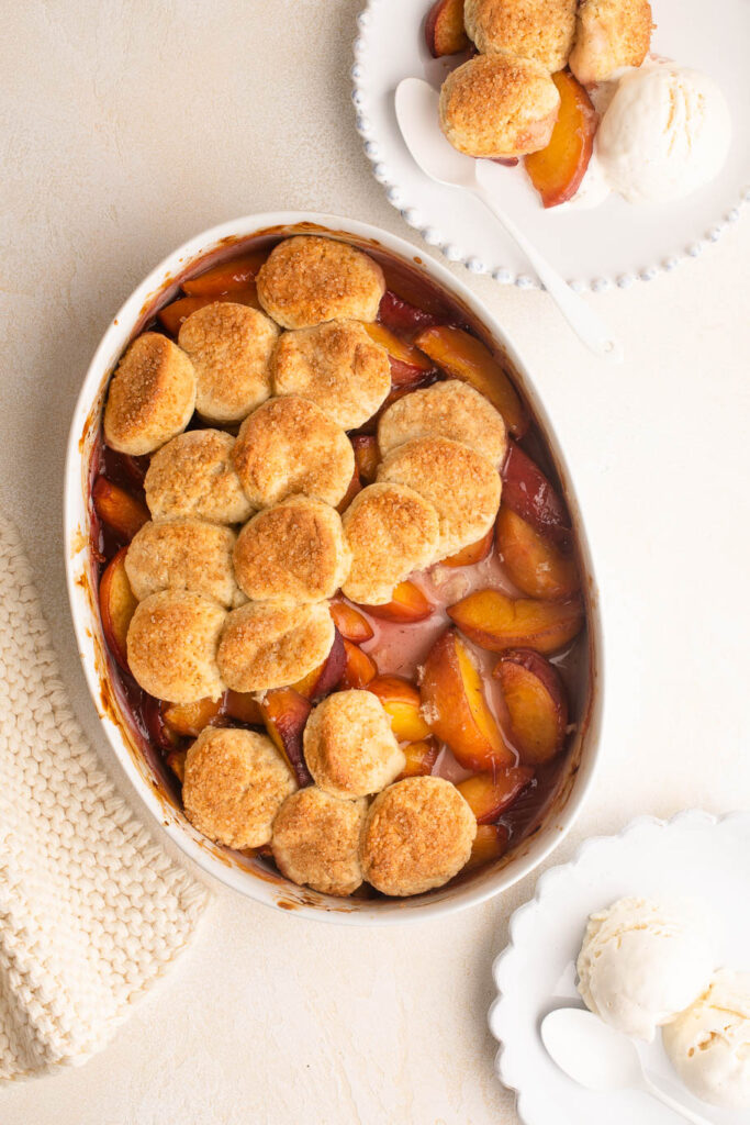 peach cobbler with scone topping in white baking dish
