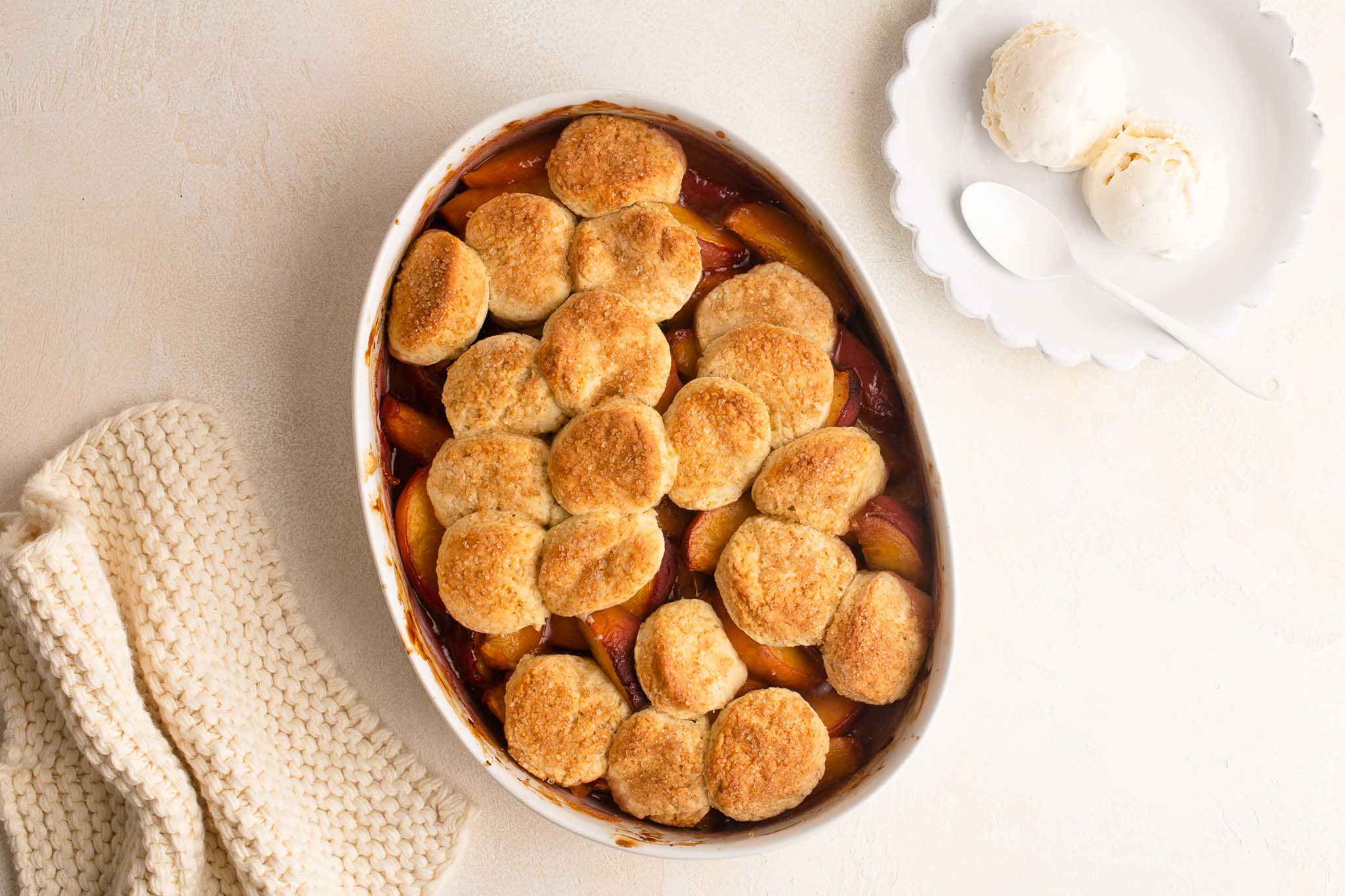 peach cobbler with scone topping and scoops of vanilla ice-cream on the side