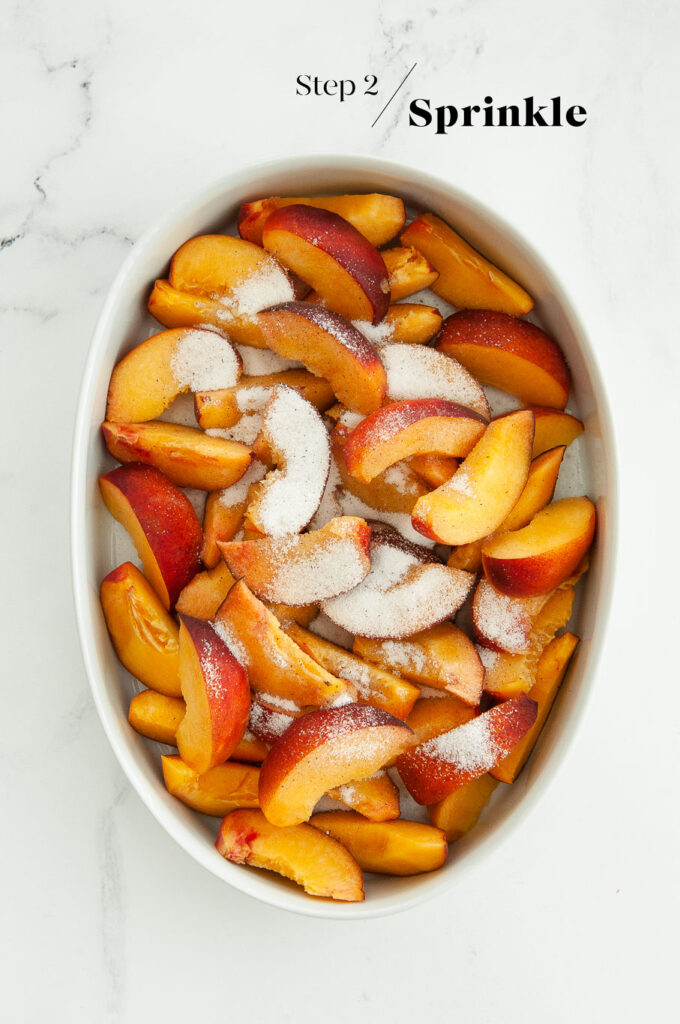 peach slices sprinkled with sugar in baking dish