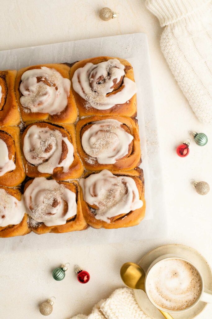 christmas cinnamon rolls with cup of coffee and christmas tree decorations