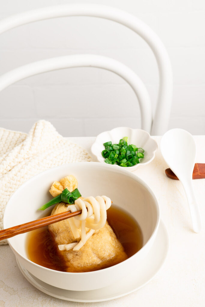 kitsune udon with chopsticks holding noodles