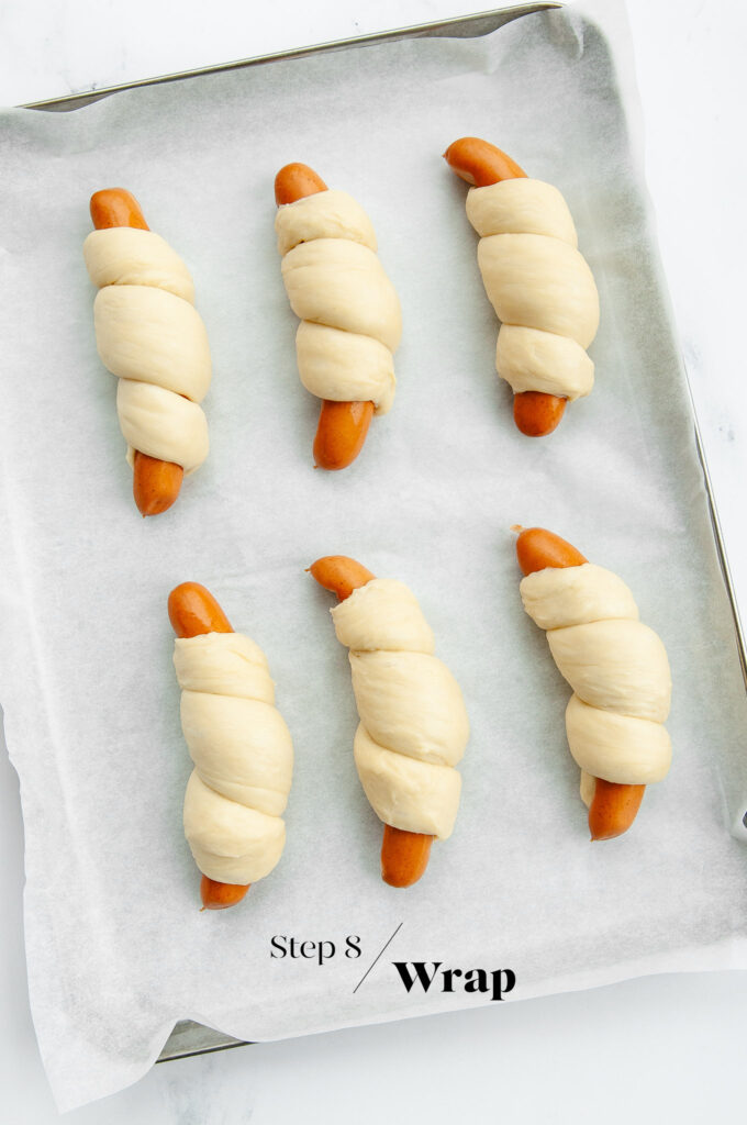 sausages wrapped in dough on baking tray
