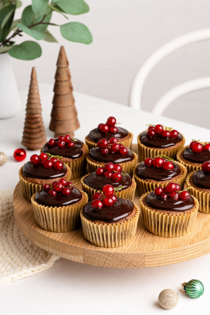 christmas cupcakes on wooden cake stand with redcurrants