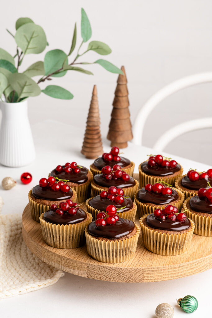 christmas cupcakes with chocolate ganache and redcurrants on wooden plate