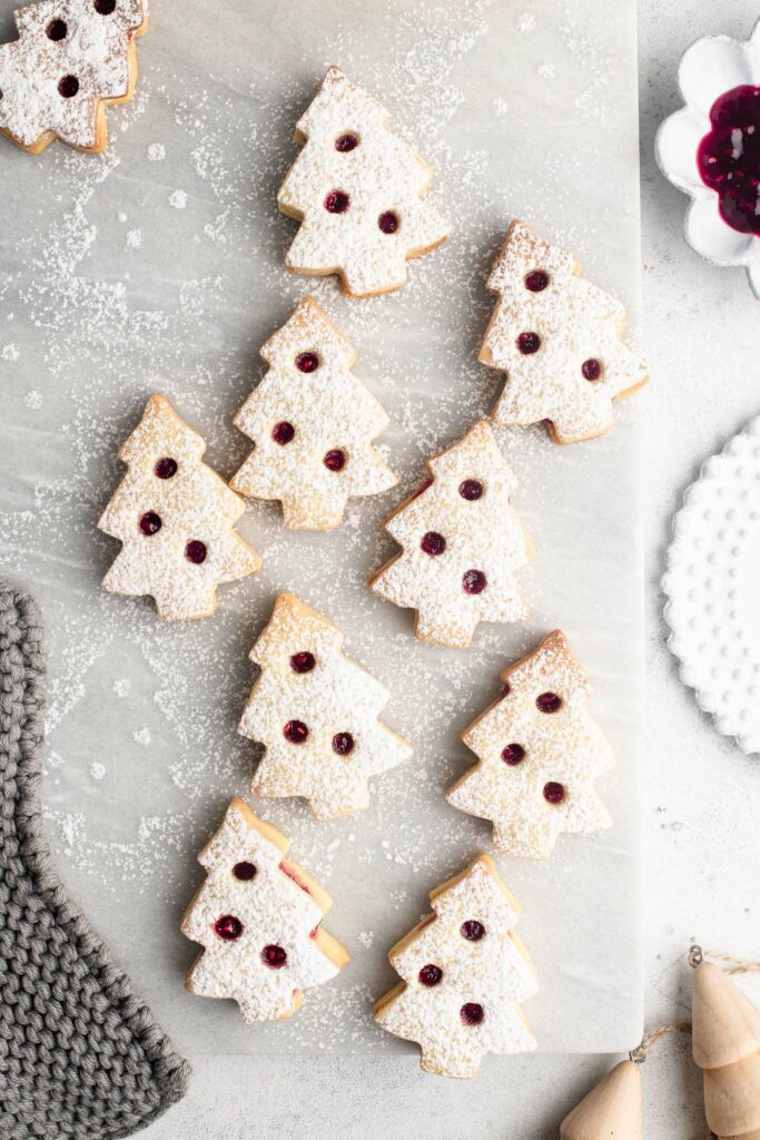 christmas tree linzer cookies dusted with icing sugar on marble plate