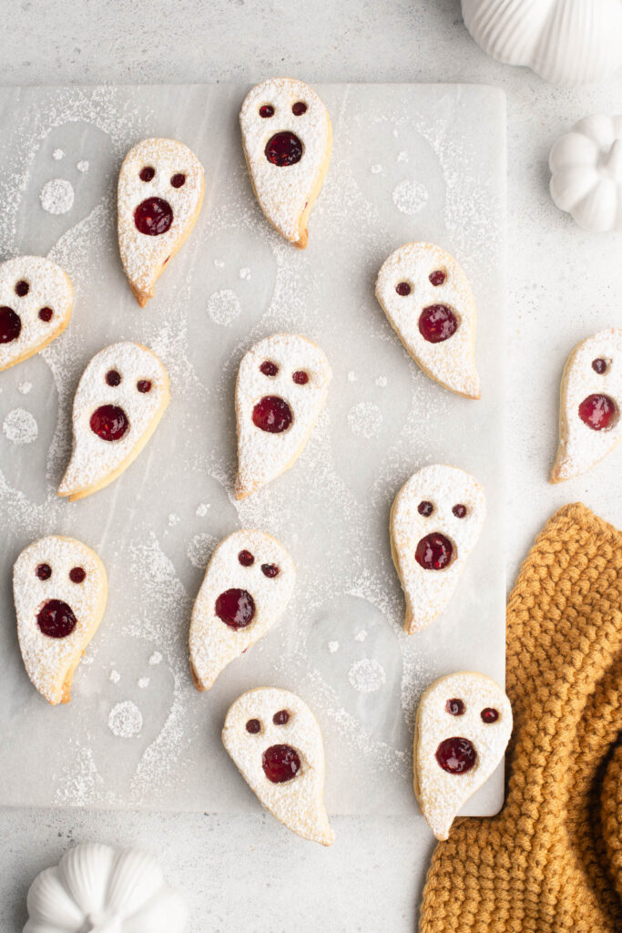 ghost linzer cookies with raspberry jam on marble tray