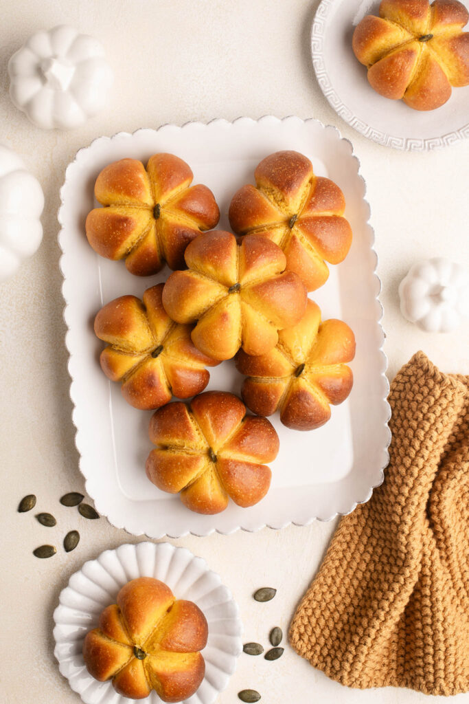 pumpkin bread rolls on white plate with pumpkin seeds