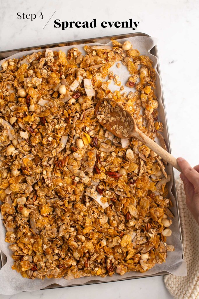 spreading granola on baking tray with wooden spoon