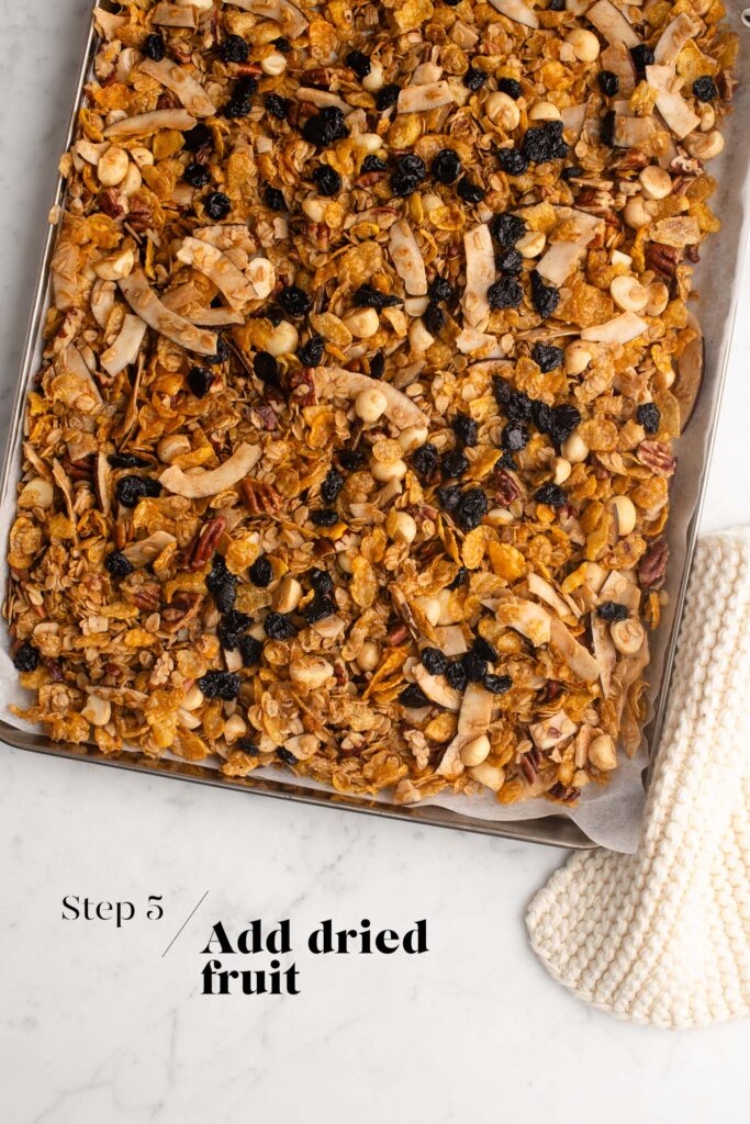 adding dried fruit to homemade granola on baking tray