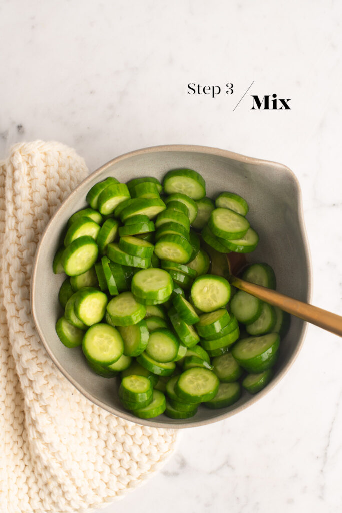 cucumber salad in small bowl with gold spoon