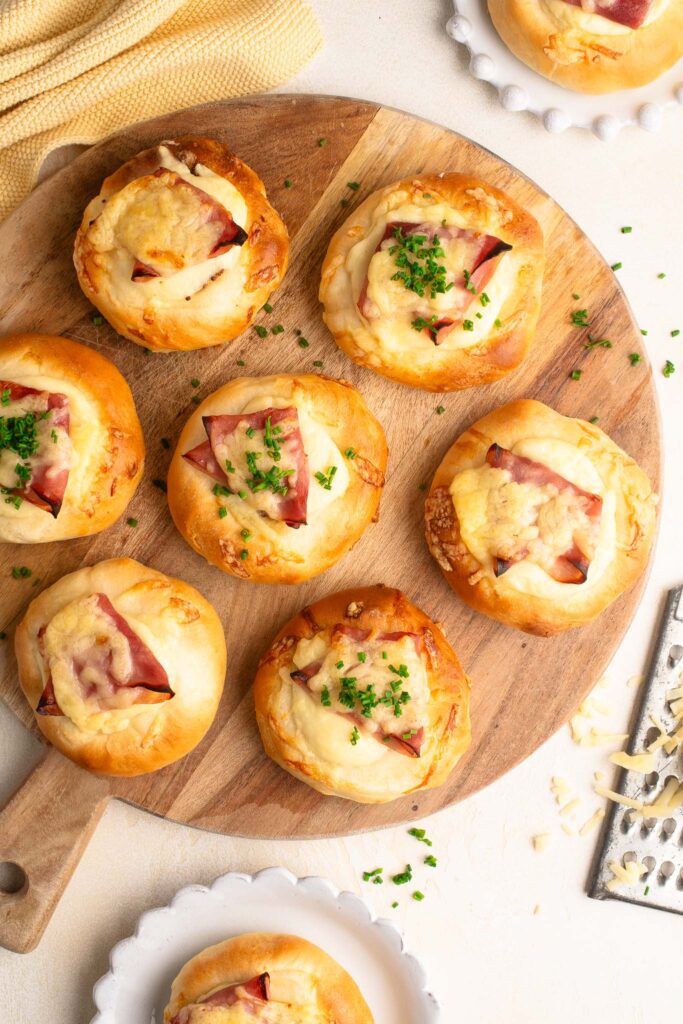 ham and cheese rolls with bechamel sauce and chives on wooden board