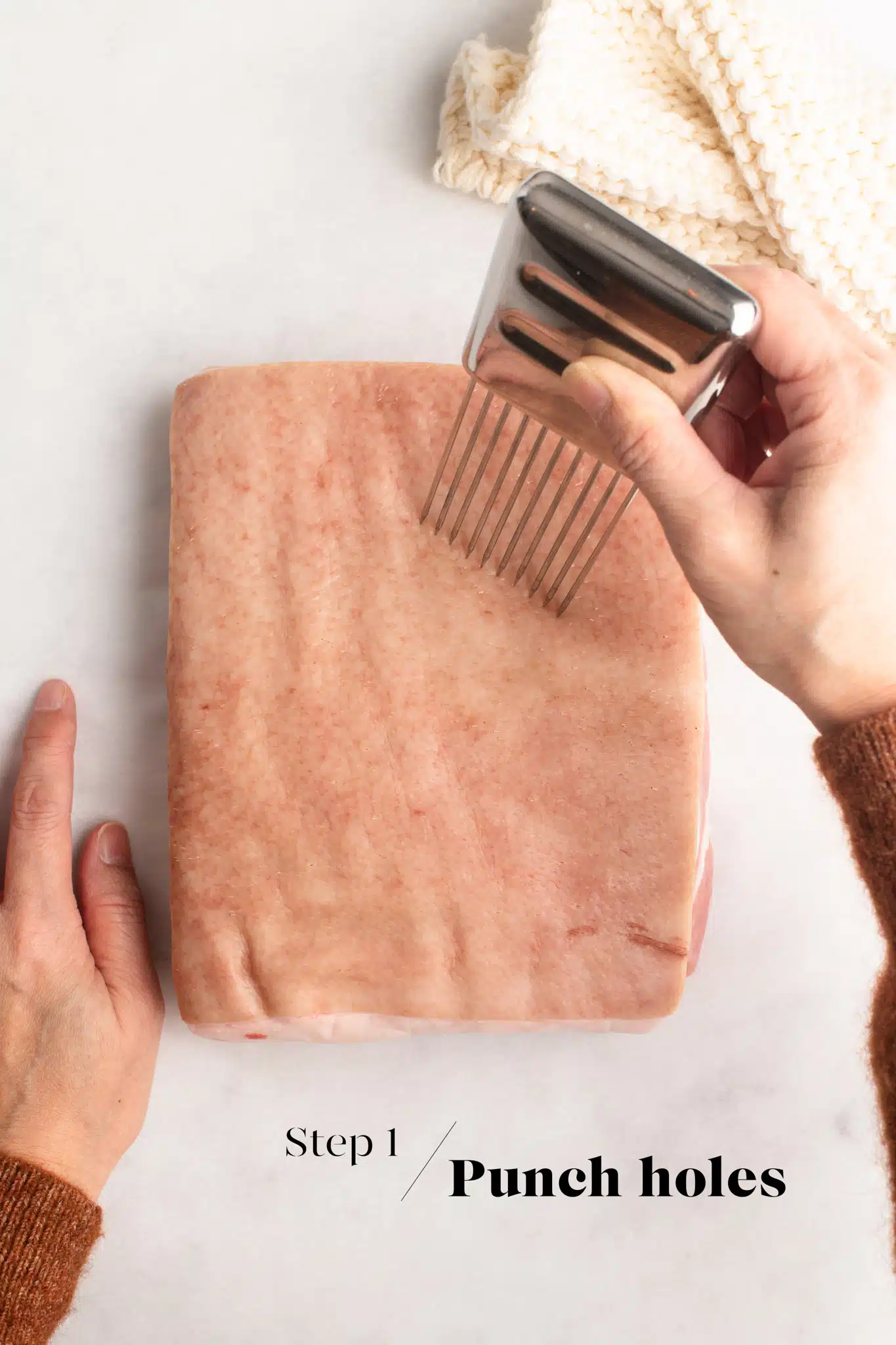 pricking the skin on pork belly with a meat tenderizer to make crispy pork belly