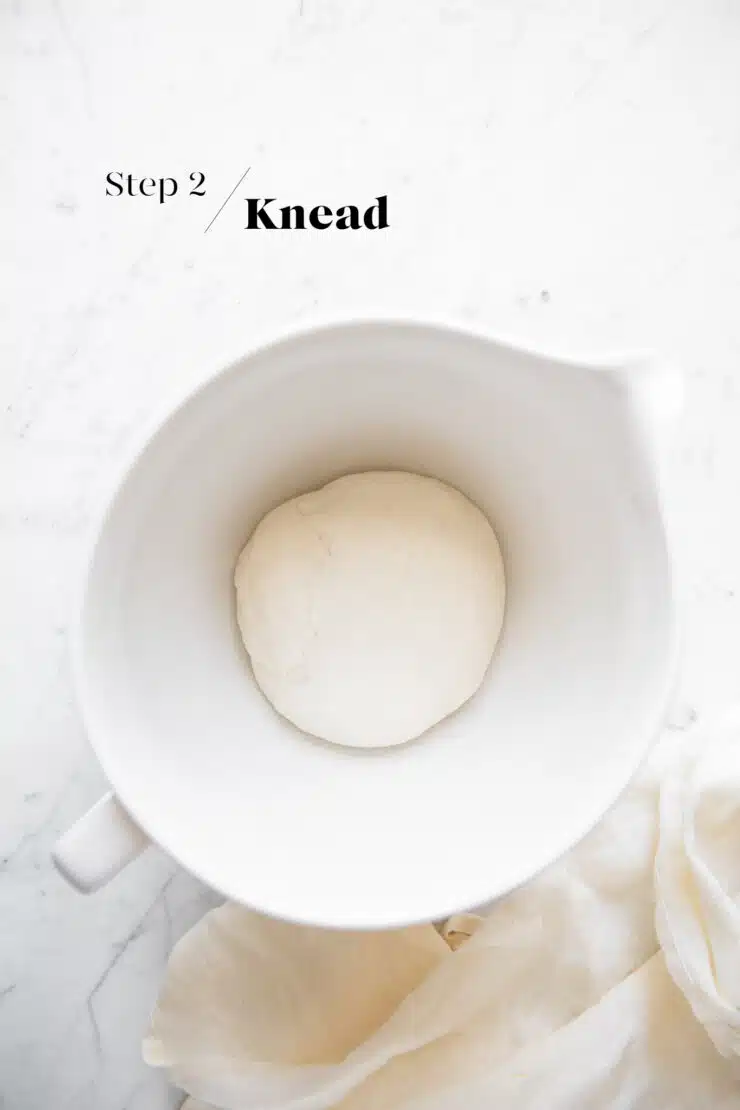 kneading dough for bao buns in white mixing bowl