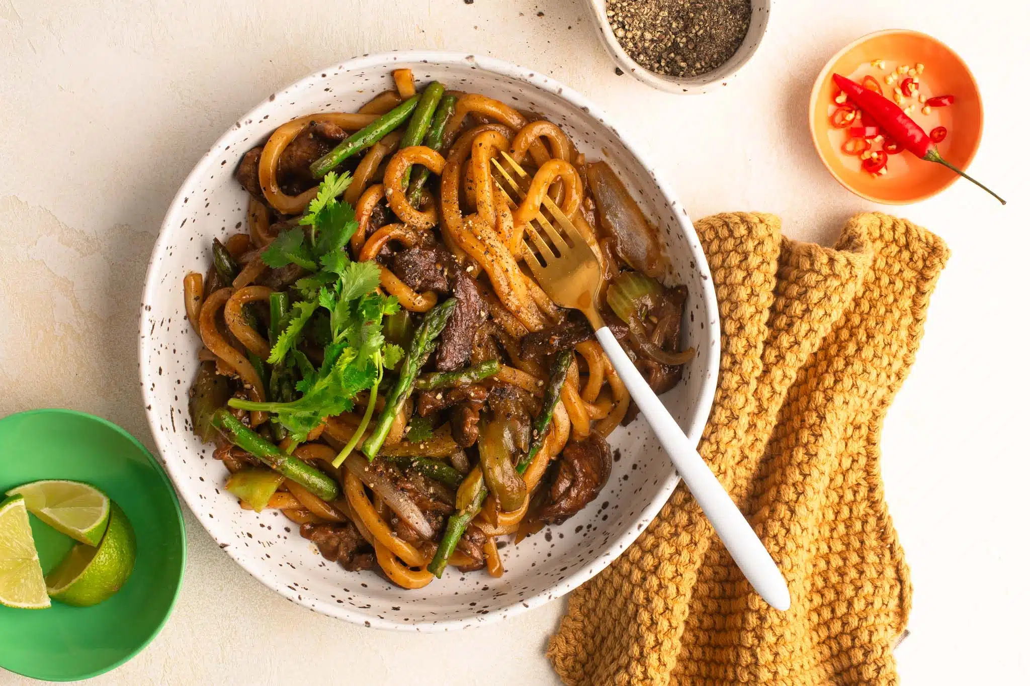 black pepper beef noodles in speckled bowl with napkin