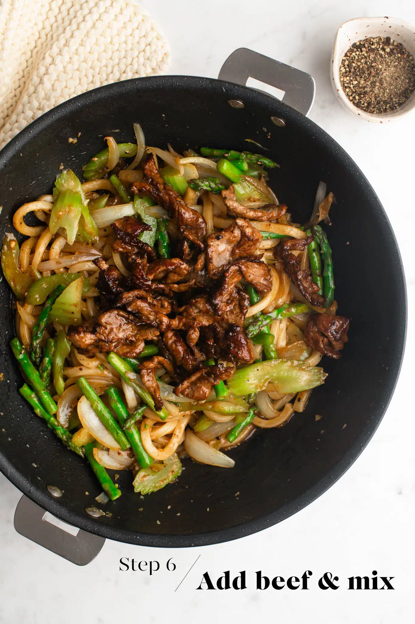 cooking black pepper beef noodles in large wok