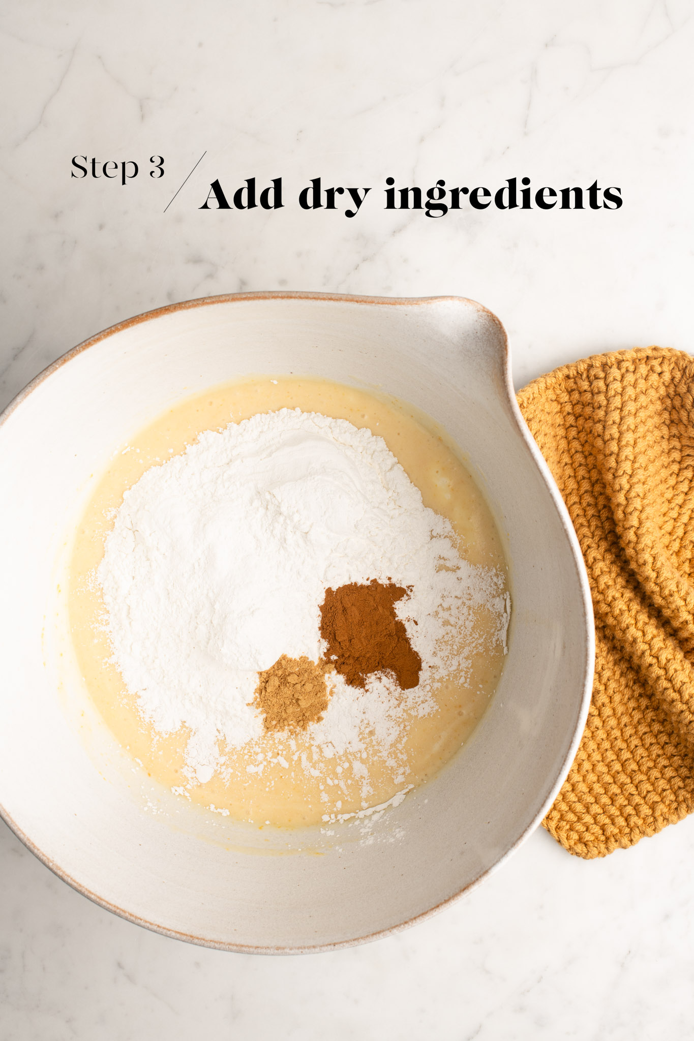 adding dry ingredients to mochi cake batter in white mixing bowl