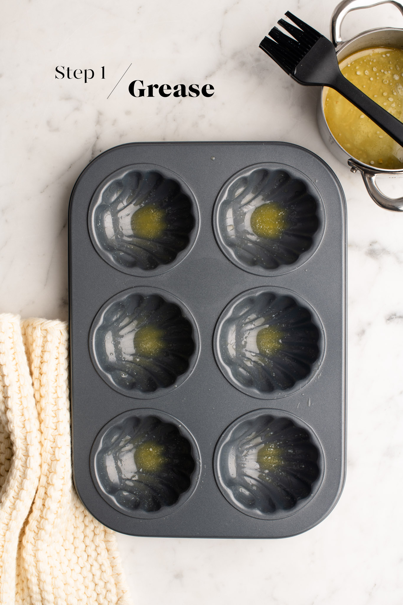 greasing a scalloped shell baking mould with butter
