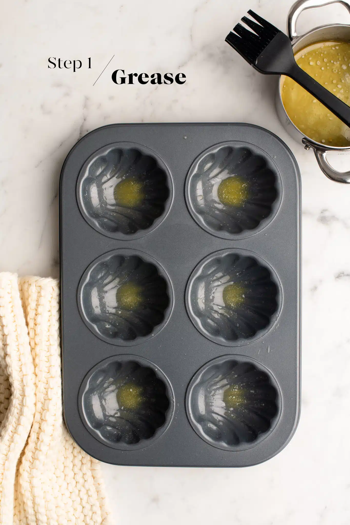 greasing a scalloped shell baking mould with butter