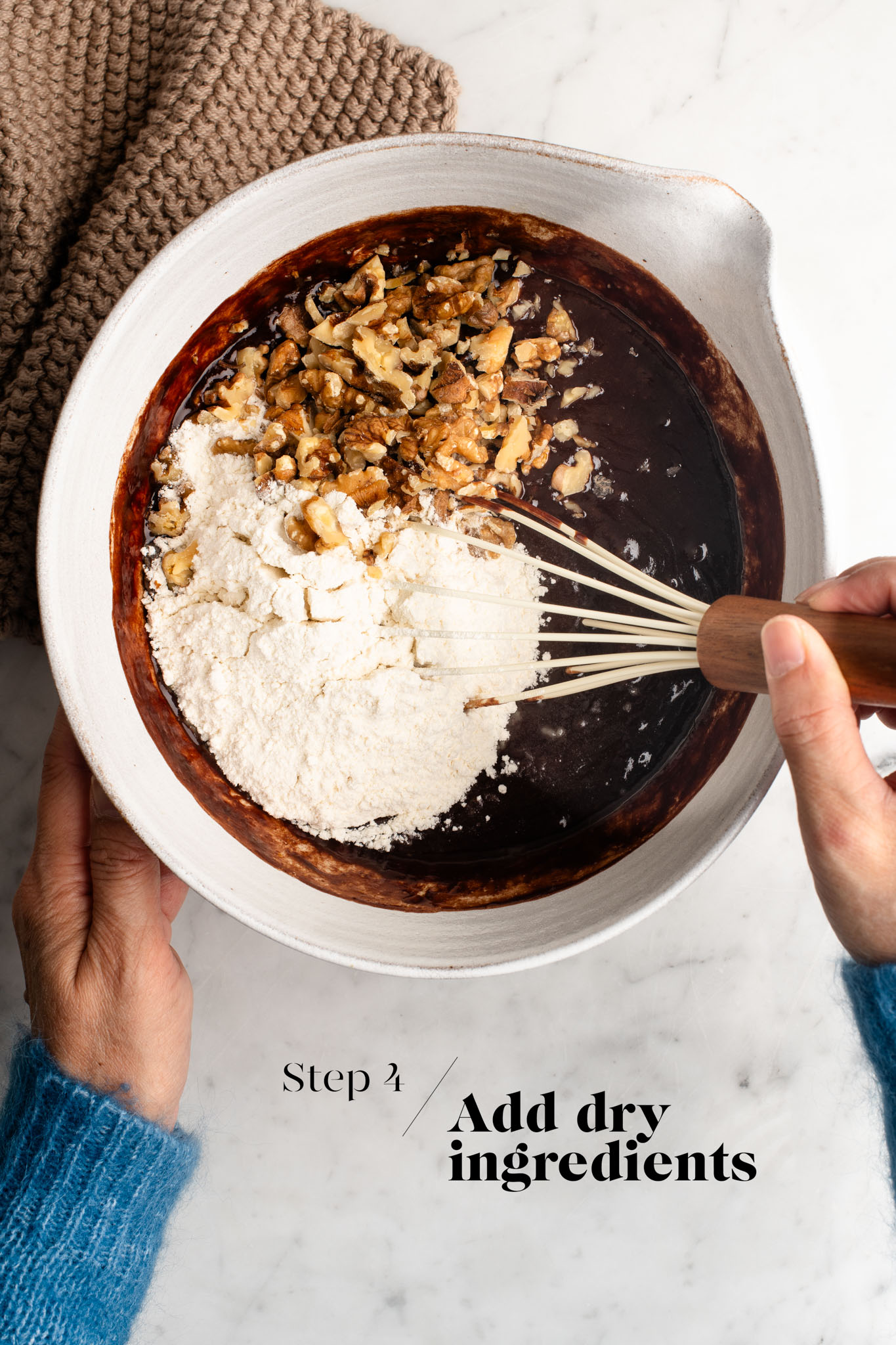 adding nuts to brownie batter in white mixing bowl