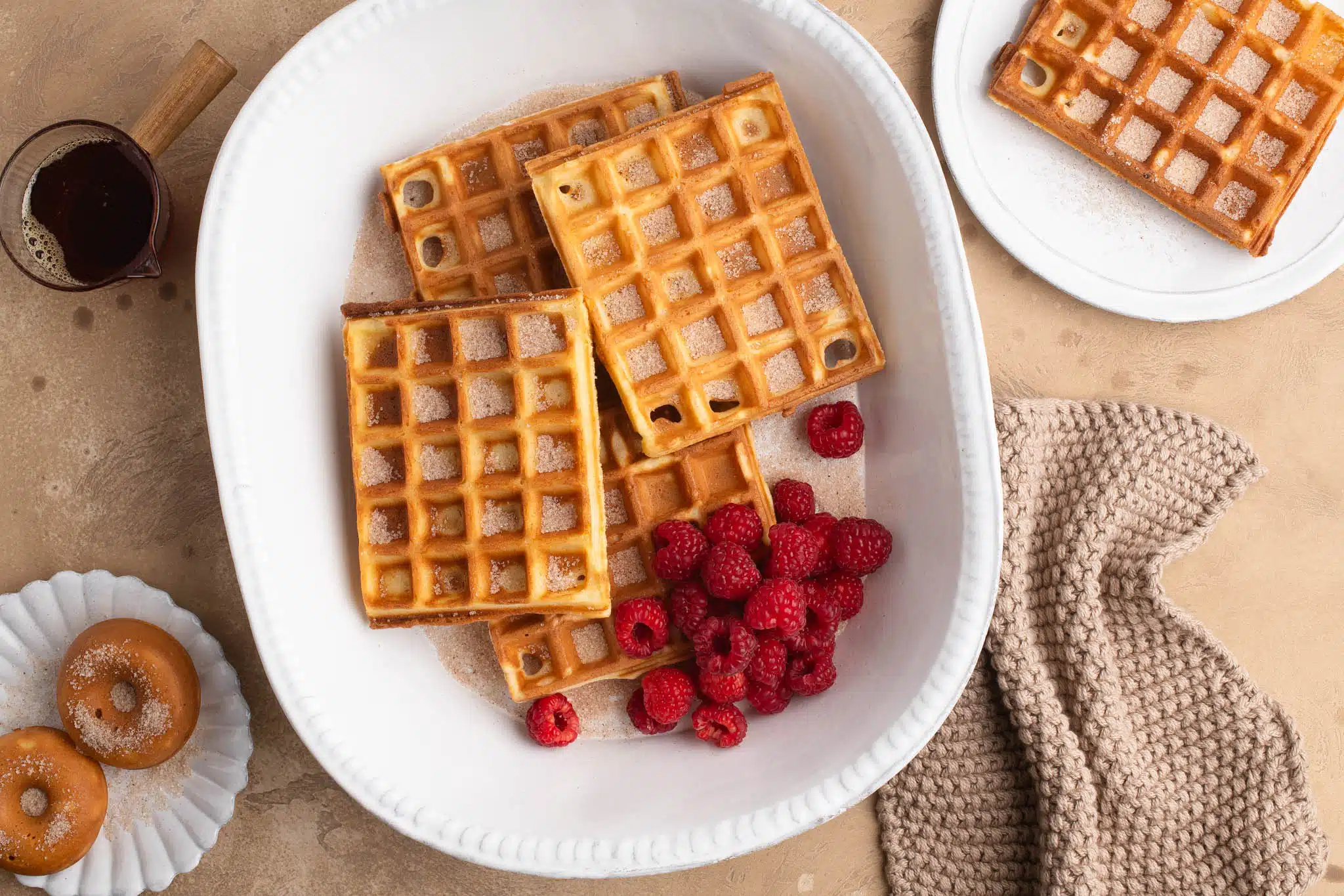 mochi waffles with cinnamon sugar and raspberries on large white plate